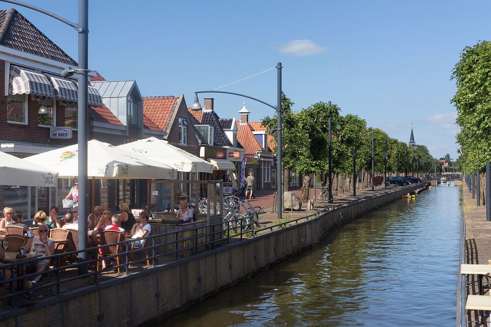 Vol terras met parasols aan het water van de Luts in Balk, met winkels en gevels langs de kade